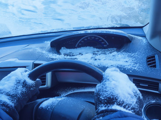 driver's hands in gloves in a frozen car