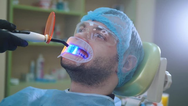 Doctor and patient with retractor in the dental office, ultraviolet and orange protective screen