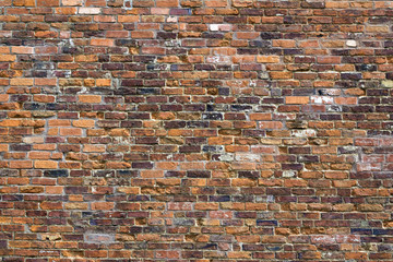 Weathered old red brick wall on a building in Winchcombe, Gloucestershire, UK.