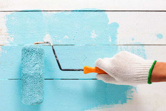 Hand painting blue color on white wooden table.