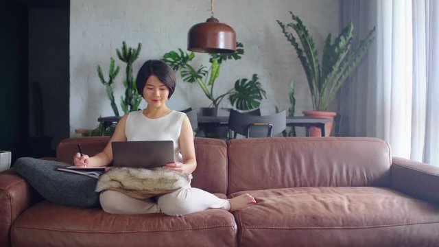 Happy Asian woman using the computer at home.