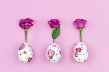 Happy Easter and Spring is coming concept. Fresh spring's red flowers roses grow from easter eggs with flower pattern on pink background.
