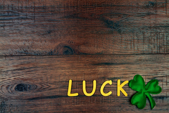 Saint Patrick's Day. Wooden letters "Luck" lying on wooden background with green three petal clover