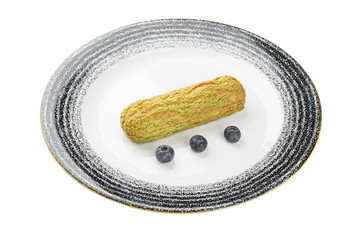 pistachio eclair on a plate. isolated on a white background