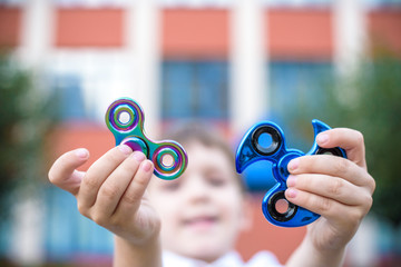 Boy playing with two fidget spinner stress relieving toys outdoor