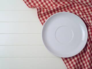 White plate on red checked tablecloth