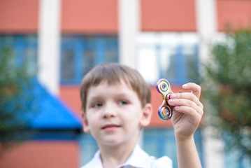 Cute little boy playing with fidget hand spinner in summer day. Popular and trendy toy for children...