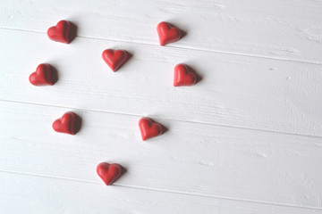 Red candies on the white wooden table. Background for greeting card on Valentine's day with place for text.