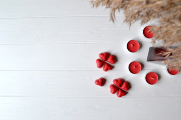 Red candy and red candle on the white wooden table. Background for greeting card on Valentine's day with place for text.
