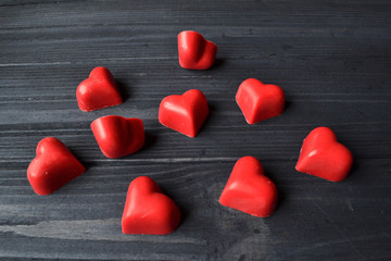 Red candies in a form of heart on the dark blue wooden background. Macro shot. Background for greeting card on Valentine's Day.