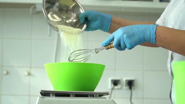Adding flour to the dough. Chef hands pouring white flour to the dough in bowl.