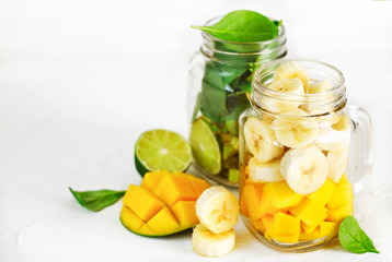 Ingredients for Banana Mango Smoothie and Green Spinach Avocado Smoothie  in mason jars. Healthy vegan eating.