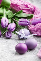 Obraz na płótnie Canvas luxurious fresh fashionable purple tulips on a wooden background next to Easter eggs