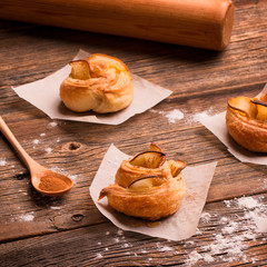 Fresh buns with pear and cinnamon on a wooden background