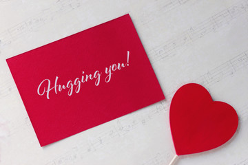 Valentines day greeting card with red heart white paper background and lettering.
