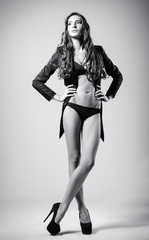 Studio fashion shot: beautiful sexy young woman wearing black lingerie and jacket. Black and white