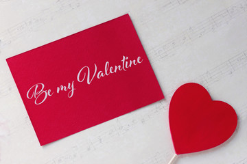 Valentines day greeting card with red heart white paper background and lettering.