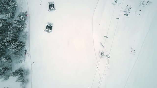 Aerial top down view of a snowcats or snow groomers on a ski resort slope in winter