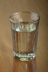 full of water or alcohol faceted drink glass with reflection