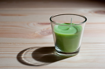 .Aromatic candle is green with the smell of tea tree on a dark background