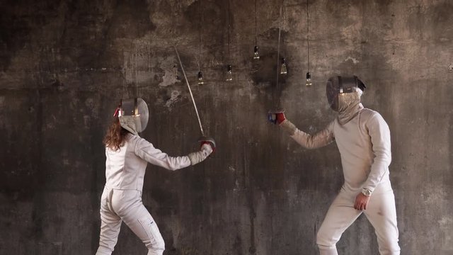 Professional swordsmen are having a practice duel in the studio. They are standing still and practice moves.