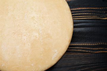 Whole round Head of parmesan or parmigiano hard cheese on wooden background