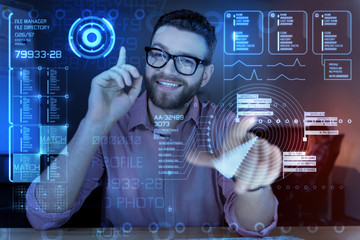 Good idea. Cheerful young smart programmer looking glad while sitting with his finger up and smiling while having a wonderful idea connected with the last cyber attack