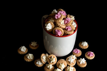 kleine Cupcakes in einer Tasse vor schwarzen Hintergrund