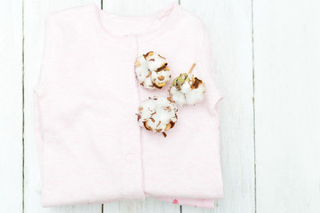 Baby eco-friendly clothing with cotton on wooden background. Flat lay