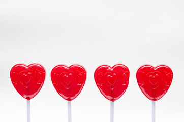 Four red lollipops against white background. Valentine's Day celebration
