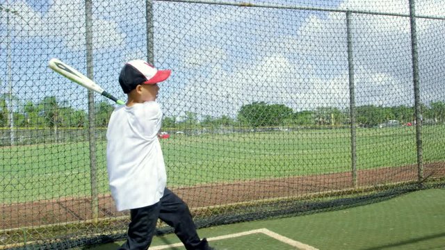 Slow motion of kid hitting ball inside batting cages at baseball park