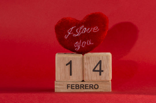 Fluffy heart, big wooden cubes forming the number fourteen and little rectangle with the word febrero against red background for Valentine's Day