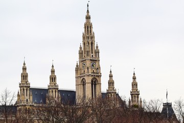 A large tower with a clock and a knight on the spire and four small towers in the center of Vienna.