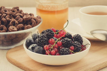 breakfast with fresh berries, flakes, honey and a cup of tea/breakfast with fresh berries, flakes, honey and a cup of tea. selective focus
