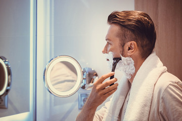 Man shaving with razor in the bathroom.