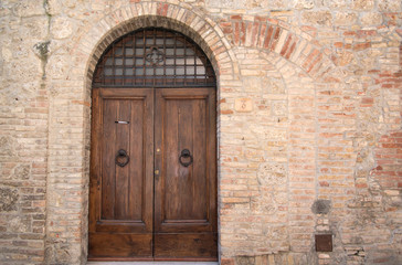 Fototapeta na wymiar Old door in brick wall with remnants of old entrances present