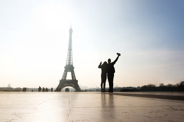 Couple at Eiffel Tower. Travelers and tourists exploring the world and the city of Paris. Romantic lovers on honeymoon or friends having fun. Silhouette people sightseeing. Wanderlust and travel.