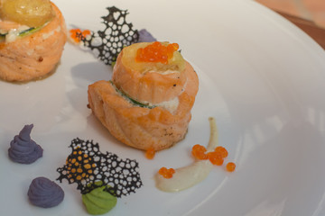 Baked salmon with cucumber,red caviar,cheese and sauce on white plate closeup - dinner in restaurant