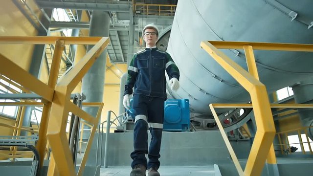 Engineer in hardhat is walking in heavy industry factory