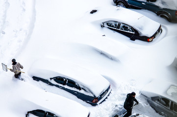 After a snowstorm, people dig out cars from under snow