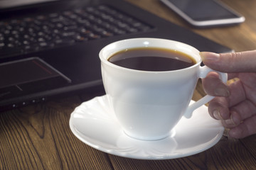 White coffee cup laptop phone hand, on a wooden background