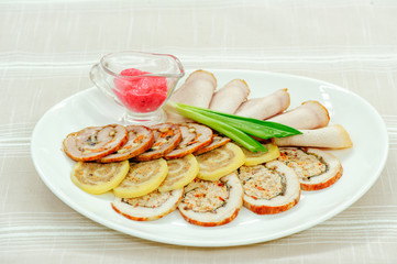 sliced delicious meat rolls on a white plate with horseradish and spring onion, restaurant serve, table setting