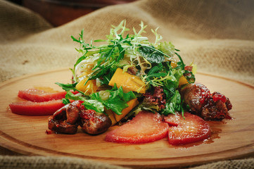 exquisite salad with mango and meat wooden background, table laying, cozy restaurant serving close-up
