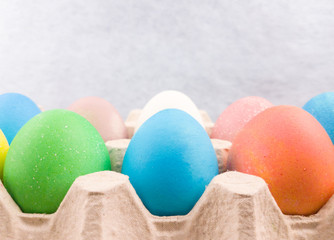 Easter color eggs in paper box on blue pastel background. Close up macro.