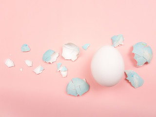 Easter color egg shell around the cooked egg on a pastel pink background. Close up macro.