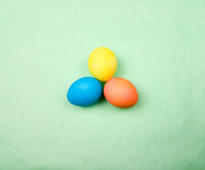 Color easter eggs on pastel green background. Close up.