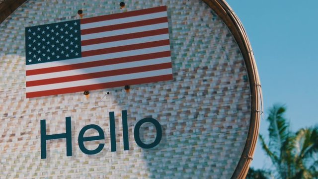 Beautiful sign with American flag with the inscription Hello in English. Sign with the inscription Hello on background of palm trees in hot Thailand