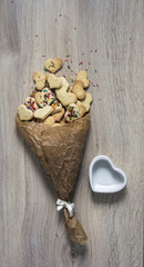 on a wooden table lies a pile of crumpled paper with cookies in the form of hearts and a pile of colorful and  heart