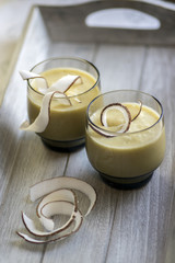Pineapple smoothie with bananas, oatmeals and coconut milk, decorated with coconut chips, wooden breakfast tray