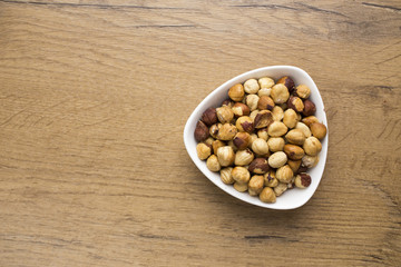 healthy raw hazelnuts in white bowl on wooden table